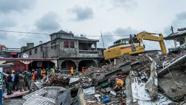 Satu buldoser membersihkan puing-puing bangunan yang runtuh akibat gempa di Brefet, lingkungan Les Cayes, Haiti, pada Selasa 17 Agustus 2021. (Foto: AFP)