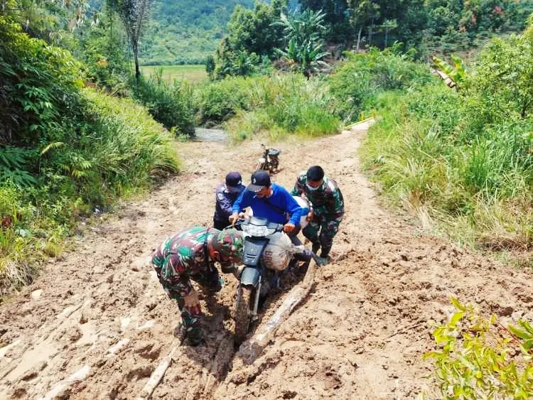 Masyarakat yang berupaya melintasi longsor tampak di bantu aparat TNI wabilkhusus Babinsa Desa Pematang Pauh, Praka Frengki Akino dari Koramil 05 Jangkat.